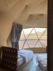 a bedroom with a large window with a bed and a chair at Noof Rum camp in Disah