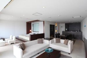 a living room with two white couches and a bed at Hotel Setre Kobe Maiko in Kobe