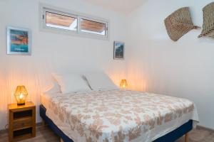 ein Schlafzimmer mit einem Bett mit zwei Lampen und zwei Fenstern in der Unterkunft Le Rêve Tropical proximité plage et commerces in Punaauia