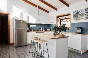 a kitchen with white cabinets and a stainless steel refrigerator at Buttons By The Beach - beach house on King Island 