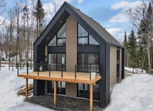 a tiny house with a black roof in the snow at Le Chamonix/Mountain view/Golf course/Activities! in Saint-Faustin