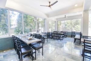 a dining room with tables and chairs and large windows at Kantara Hotel By BIL in Lonavala