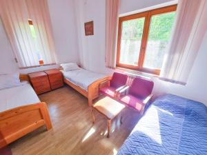 1 dormitorio con 2 camas, silla y ventana en Zlatni Pir Rooms and Apartments, en Sarajevo