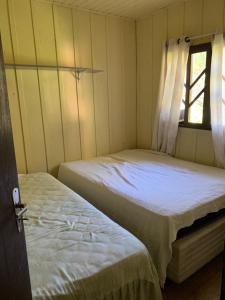 Duas camas num pequeno quarto com uma janela em Recanto Vale Verde em São Bento do Sul