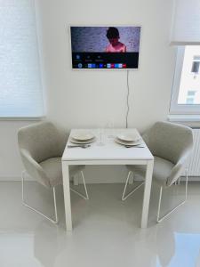 mesa blanca con 2 sillas y TV en la pared en White House Vienna, en Viena