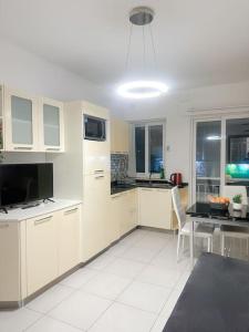 a kitchen with white cabinets and a table and chairs at Cozy Central Apartment - Swieqi in Is-Swieqi
