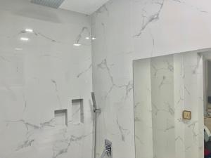 a white bathroom with a mirror and a shower at Dhonveli Stay in Hulhumale