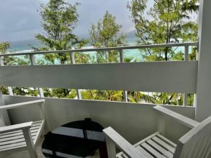 a balcony with white chairs and a table and trees at Dhonveli Stay in Hulhumale