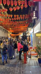 a crowd of people walking through a shopping street with lanterns at Little wooden hut in London