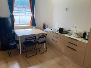cocina con mesa, 2 sillas y escritorio en Little wooden hut en Londres