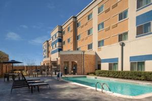 a hotel with a pool and tables and a building at Courtyard by Marriott Houston Northwest/Cypress in Cypress