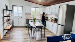 a woman standing in a kitchen with a table at The Biscuit House in Praia da Vitória