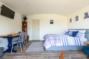 a bedroom with a bed and a desk and a table at Pear Tree Cabin in Whitstable