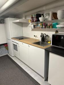 una piccola cucina con armadi bianchi e lavandino di Mysigt centralt boende a Göteborg