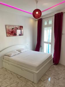 a bedroom with a white bed with red curtains at Appartement coeur de ville Tunis in Tunis