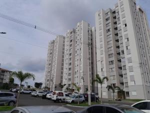 un estacionamiento con autos estacionados frente a edificios altos en Apartamento do Remanso 2/4, en Hortolândia