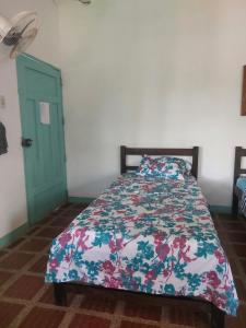 1 dormitorio con 1 cama con edredón de flores en Cabaña Ecoturismo Los Mangos, en Santa Marta