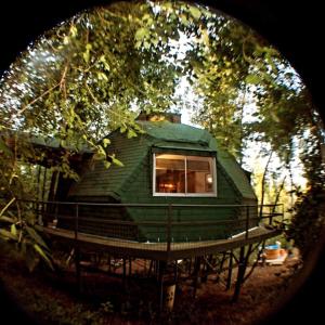 a green tree house with a window on a platform at Glamping Domo Valle de Rabones in Colbún Alto