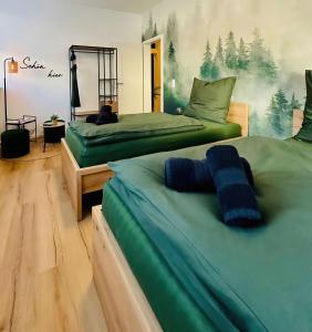duas camas verdes num quarto com árvores na parede em Apartment Schwarzwaldgeflüster em Gernsbach