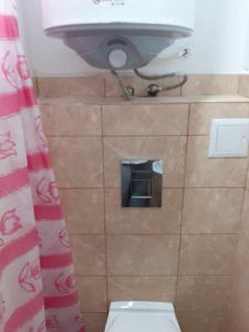 a bathroom with a toilet with a sink and a toilet paper holder at Самостоятелна малка стая in Varna City