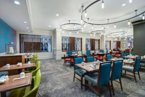 um restaurante com mesas de madeira e cadeiras azuis em Hilton Garden Inn Terre Haute em Terre Haute