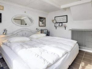 a white bedroom with a large white bed and a mirror at 5 person holiday home in Løkken-By Traum in Løkken