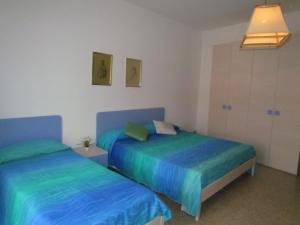 2 letti in una camera con lenzuola blu e verdi di Large Apartment for up to 9 guests - Great Location - Including Beach Place a Bibione