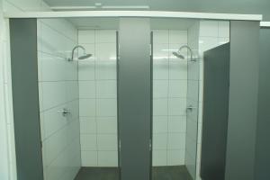La salle de bains est pourvue de 2 cabines de douche et de portes en verre. dans l'établissement Melbourne City Backpackers, à Melbourne