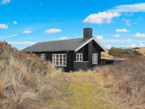 uma casa negra sentada no topo de uma colina em Holiday home Brovst XI em Brovst