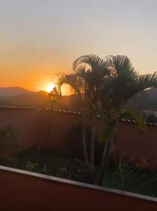 un coucher de soleil avec des palmiers devant une clôture dans l'établissement Casa vista da serra, à Tiradentes