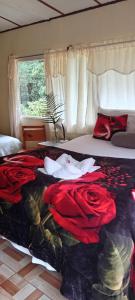a bedroom with a bed with red roses on it at Miriam'S Quetzals lodge in San Gerardo de Dota
