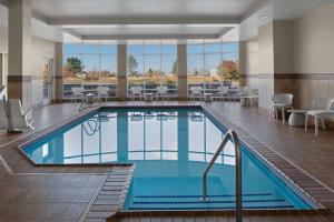 una piscina en una habitación de hotel con mesas y sillas en Hilton Garden Inn - Salt Lake City Airport, en Salt Lake City