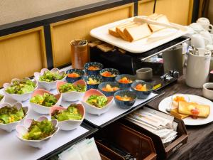 a buffet with bowls of food on a table at Iga Ueno City Hotel in Iga