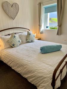 a bed with a blue pillow on top of it at Beautiful Cottage Short Walk To Porth Beach in Newquay