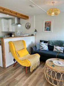 a living room with a yellow chair and a couch at Beautiful Cottage Short Walk To Porth Beach in Newquay