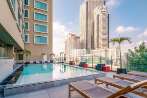 a swimming pool with benches and tall buildings at Hilton Garden Inn Bangkok Silom in Bangkok