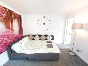 a bedroom with a couch and a clock on the wall at The Blossom - Largs in Largs