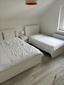 2 Betten in einem Schlafzimmer mit weißen Wänden und Holzböden in der Unterkunft Hagen Haspe 2Z DG in Hagen