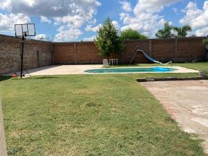 a backyard with a basketball hoop and an empty pool at CCasa con piscina para 8 personas in Mercedes