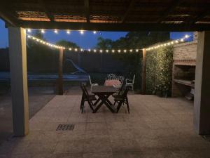 a patio with a table and chairs and lights at CCasa con piscina para 8 personas in Mercedes