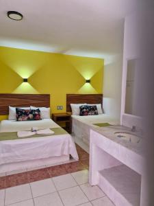a hotel room with two beds and a sink at Hotel Capri Playa a una calle de la Playa Regatas in Veracruz