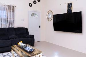 sala de estar con sofá negro y TV en Your ideal home away from home., en The Rock