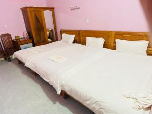 a bedroom with two beds with white sheets at Nhà nghỉ Thiên Phúc in Mộc Châu