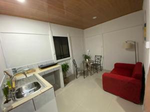sala de estar con sofá rojo y cocina en The Sloth Retreat & Studio Fortuna en Fortuna