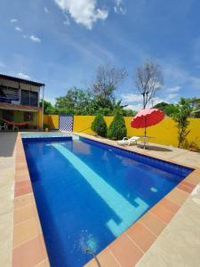 a blue swimming pool with an umbrella next to a yellow wall at CASA QUINTA VILLA ESPERANZA in Guayabal