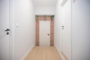 an empty hallway with a white door and a brick wall at Aerostay Hostel in Moreira