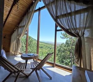 a room with chairs and a table and a large window at Chalés do Tabuleiro Pousada Rural in Palhoça