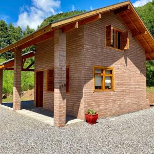 una casa de ladrillo con una maceta de flores rojas delante de ella en Villetta Gramado Siena, en Gramado