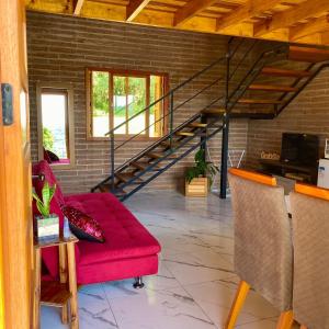 sala de estar con sofá rojo y escaleras en Villetta Gramado Siena, en Gramado