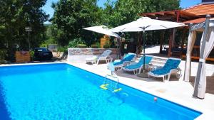 a swimming pool with chairs and an umbrella at Family friendly house with a swimming pool Imotski, Zagora - 22880 in Imotski